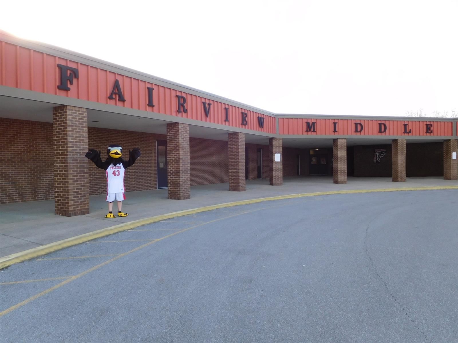  A falcon mascot stands in front of a school building